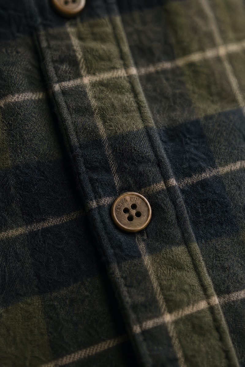 Close-up of a green and navy plaid brushed-cotton flannel overshirt with branded buttons